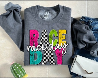 May include: A gray sweatshirt with a colorful graphic design that says "RACE" with "raceday" written in cursive underneath. The graphic has a checkered flag pattern and a distressed look.