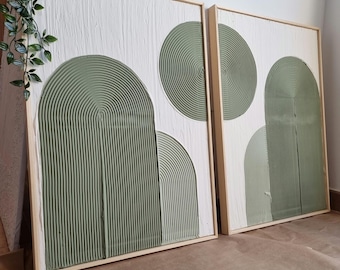 May include: Two framed abstract art pieces with a white background and green geometric shapes. The shapes are textured and have a 3D effect.