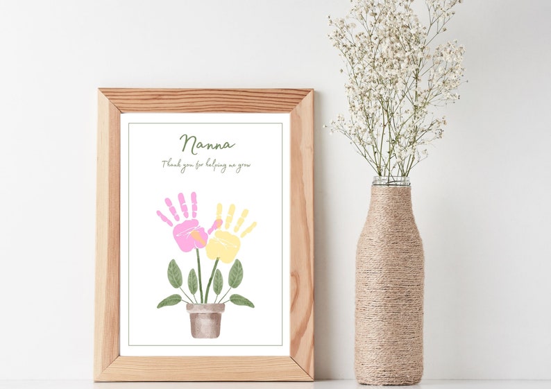 May include: A framed print featuring a handprint art design of two flowers in a pot. The text reads "Nanna, thank you for helping me grow".