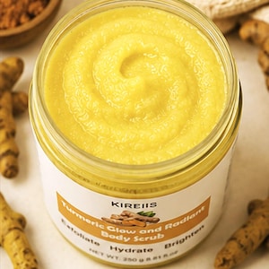 May include: A jar of turmeric body scrub with a bright yellow, swirled texture. The label reads "Turmeric Glow and Radiant Body Scrub" with the brand name "KIREIIS". The jar contains 250 g of product.