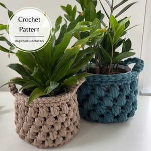 Puede incluir: Dos macetas de plantas de crochet, una de color marrón claro y la otra de color azul turquesa. Las macetas están hechas con un punto texturizado y tienen forma redonda. El texto "Crochet Pattern Dogwood Crochet US" es visible en la esquina superior izquierda de la imagen.