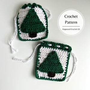 May include: Two crocheted Christmas tree gift bags with white and green yarn. The bags have drawstrings and are ready to be filled with gifts.