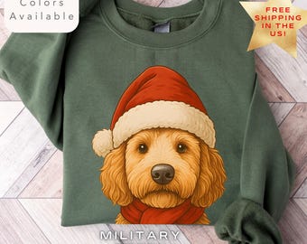 May include: Military green sweatshirt featuring a golden doodle wearing a Santa hat and red scarf. The sweatshirt has the text "Multiple Colors Available" and "Military Green".