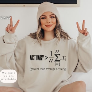 Puede incluir: Una sudadera beige con el texto "ACTUARY> 1/n Σ(i=1 to n) x_i (greater than average actuary)" impreso en la parte delantera.