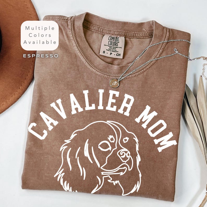 Peut inclure: T-shirt couleur expresso avec l'inscription "CAVALIER MOM" et un contour blanc d'un chien Cavalier King Charles Spaniel. Le t-shirt a un col rond et des manches courtes. Les mots "Multiple Colors Available" et "Espresso" sont dans un encadr&eacute; blanc.