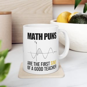 May include: White ceramic mug with a black graphic of a sine wave and the text "MATH PUNS ARE THE FIRST SINE OF A GOOD TEACHER".