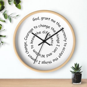 May include: A white round clock with black hands and a wooden frame. The clock face has the text "God, grant me the serenity to accept the things I cannot change, Courage to change the things I can, and Wisdom to know the difference."