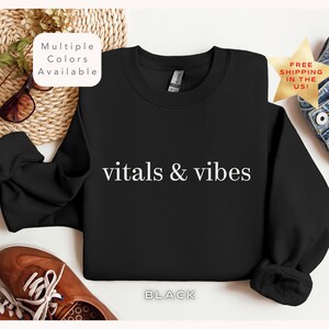 May include: Black sweatshirt with white text that reads "vitals & vibes".