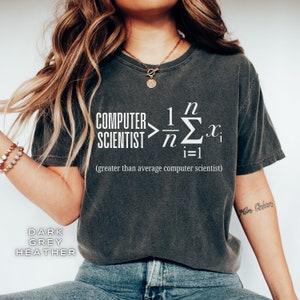 May include: Dark heather grey t-shirt with a white graphic of a math equation and the text "COMPUTER SCIENTIST > 1/n Σn=1 xi (greater than average computer scientist)"