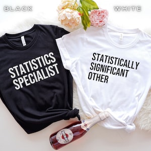 Puede incluir: Dos camisetas, una negra y una blanca, con un diseño de pareja a juego. La camiseta negra dice "Especialista en estadística" y la camiseta blanca dice "Significativamente otro estadísticamente".