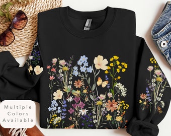 May include: Black sweatshirt with a floral print featuring a variety of colorful flowers and a butterfly. The flowers are arranged in a vertical pattern and are surrounded by green leaves.
