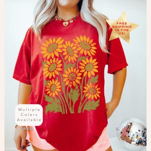 May include: Red t-shirt with a vintage-style graphic of sunflowers. The text "Multiple Colors Available" and "RED" are also visible.