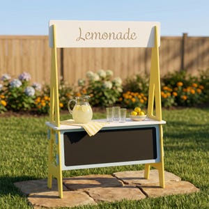 May include: A yellow and white lemonade stand with the word "Lemonade" in script. The stand has a chalkboard, a pitcher of lemonade, glasses, and a bowl of lemons. The stand is on a stone surface.