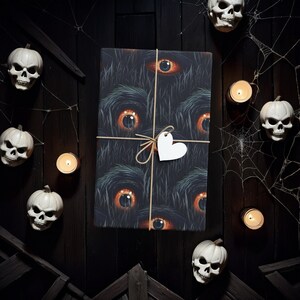 May include: A black and brown gift wrap with a repeating pattern of eyes. The gift is tied with twine and a white heart-shaped tag.