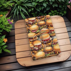 K&ouml;nnte beinhalten: Eine braune Geschenkpapierverpackung mit einem sich wiederholenden Muster aus bunten, saftigen und lecker aussehenden Hamburgern. Die Hamburger sind hoch mit K&auml;se, Salat, Tomate und Zwiebel belegt.