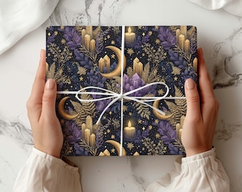 Può includere: Una scatola regalo rettangolare avvolta in carta blu scuro con un motivo ripetuto di lune crescenti dorate, candele accese, grappoli di cristalli viola e foglie di felce dorate, legata con un sottile spago bianco a fiocco.