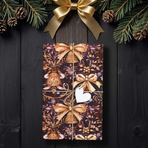 May include: A wrapped gift with a floral and bell pattern, tied with twine and a heart-shaped tag. The gift is adorned with gold bows and set against a dark wood background, with pine branches and gold bows.