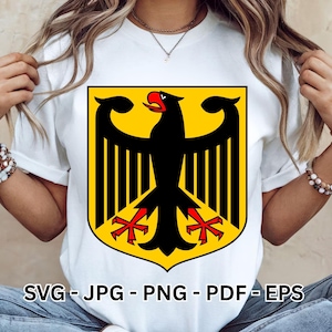 May include: A white short-sleeved t-shirt featuring a large graphic of a black eagle with a red beak and red talons centered on a yellow shield. The text SVG - JPG - PNG - PDF - EPS is printed in black at the bottom of the graphic design.