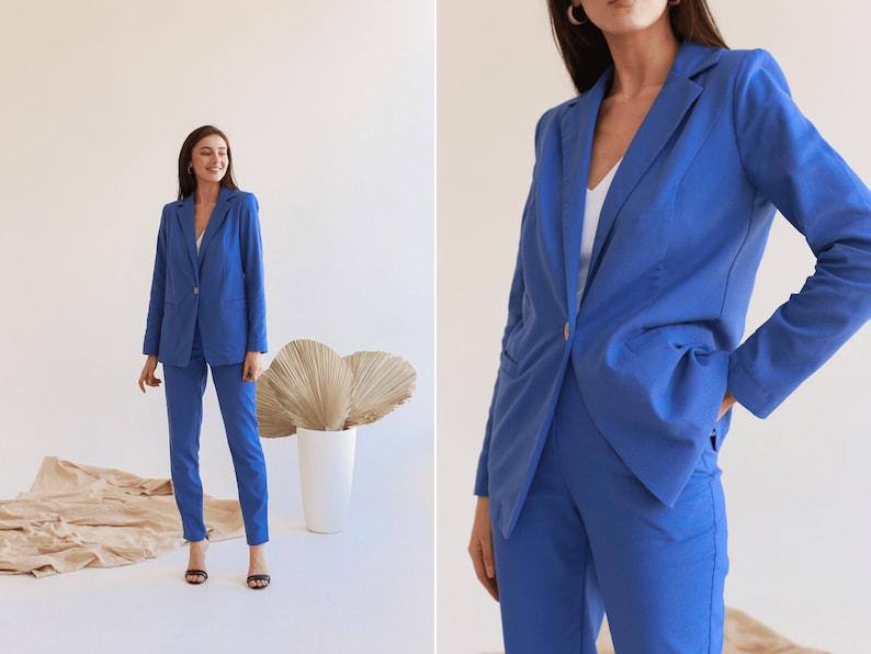 May include: A woman wearing a blue blazer and matching pants. The blazer has a single button closure and the pants have a straight leg.