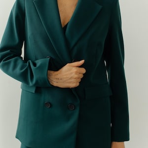 May include: A dark green double-breasted blazer with long sleeves and a matching pair of pants.