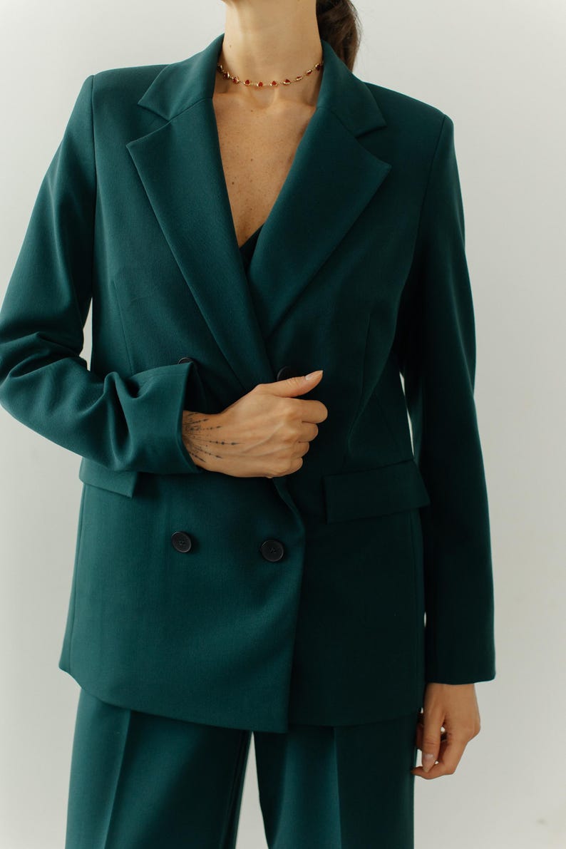 May include: A dark green double-breasted blazer with long sleeves and a matching pair of pants.