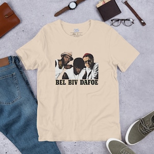 May include: A beige t-shirt with a graphic print of three men wearing hats. The text "BEL BIV DAFOE" is printed below the image.