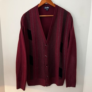 May include: A burgundy cardigan with black and grey stripes. The cardigan has a v-neck and button closure.