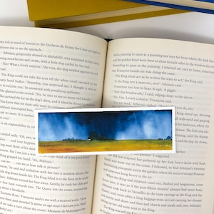 May include: A small watercolor painting of a landscape with a dark blue sky and a yellow field. The artwork is rectangular and has a simple, minimalist style, with soft brushstrokes and a focus on color.