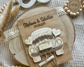 Può includere: Segno in legno con un'auto bianca ritagliata, decorata con fiori e cuori. Il cartello dice "Stephanie & Sebastian 09.08.2019" e "Just Married".