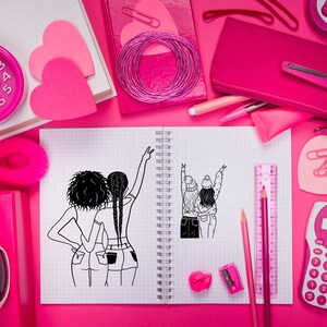 May include: A notebook with a black and white illustration of two people with their arms raised in the air. The notebook is open and has a spiral binding. There are various pink school supplies on a pink surface around the notebook.