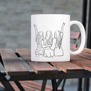 May include: White ceramic mug with a black line drawing of three women standing back to back with their arms around each other. The women are wearing casual clothing and have their hair down.