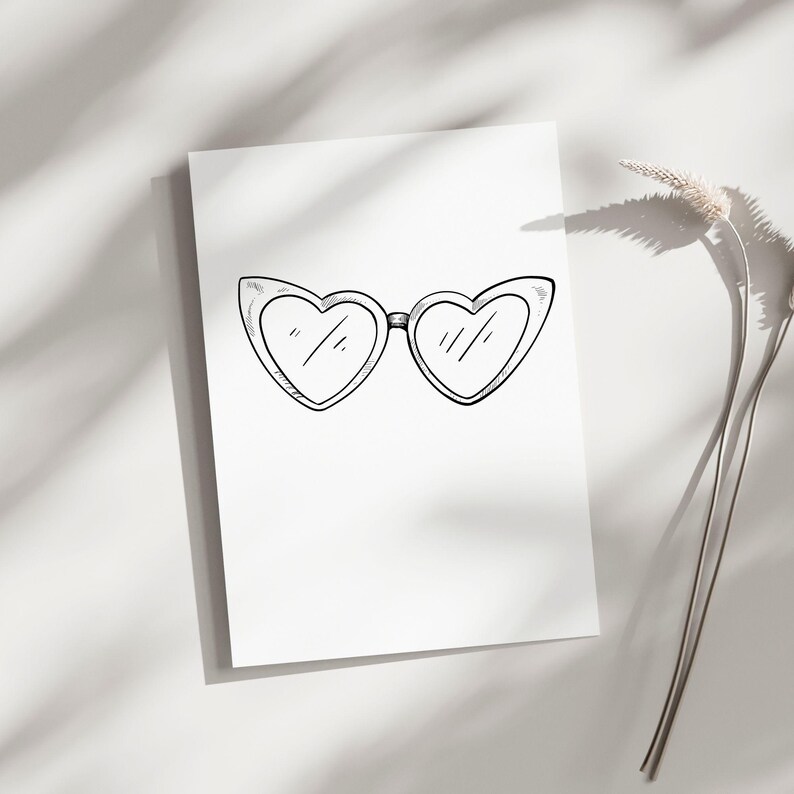 May include: A black and white illustration of heart-shaped sunglasses on a white background. The sunglasses are the focal point, with a simple, sketched design. The image is clean and minimalist, with soft shadows.