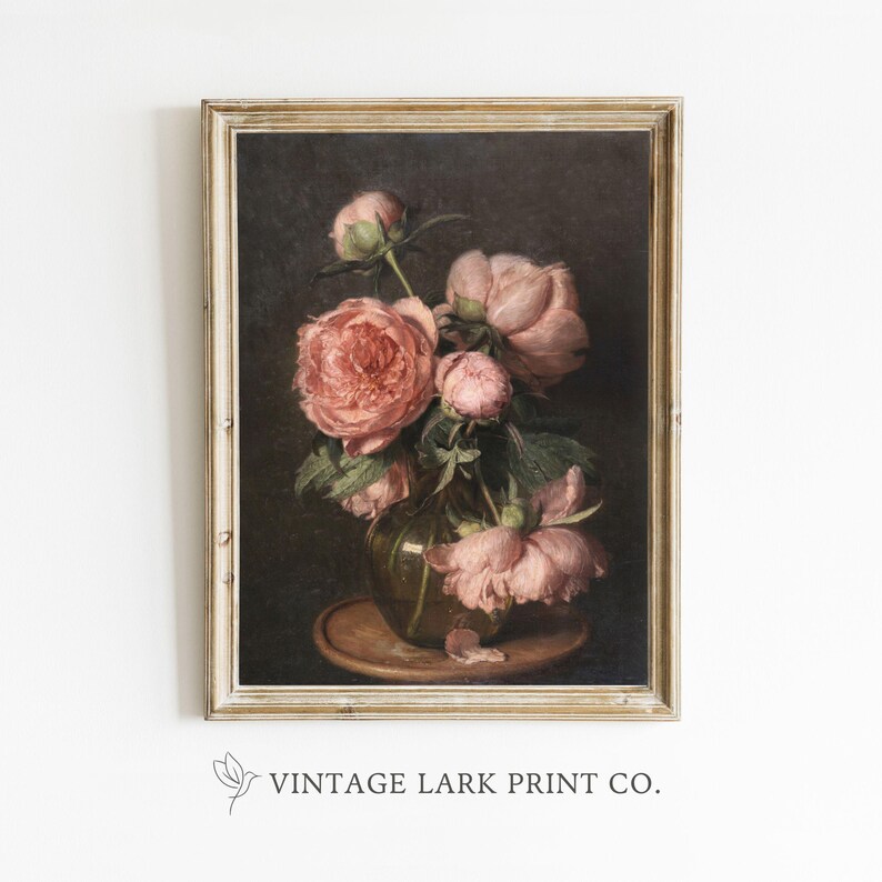 Op de afbeelding: Een vintage schilderij van een boeket roze pioenen in een glazen vaas. De bloemen zijn in een vaas op een houten tafel gerangschikt. Het schilderij is ingelijst in een lichtbruin frame.