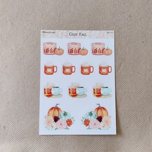 Op de afbeelding: Een vel stickers met een herfstthema. De stickers bevatten afbeeldingen van kaarsen, pompoenen, mokken met warme dranken en bloemstukken. De tekst "Cozy Fall" staat bovenaan het vel.
