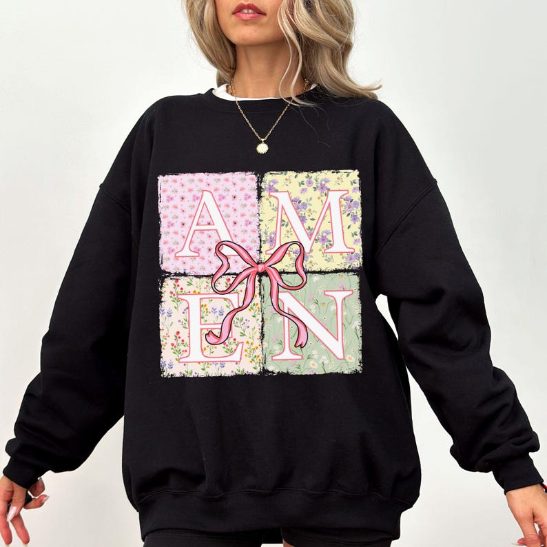 May include: Black sweatshirt with a floral print design that spells out the word "AMEN" in a patchwork style.