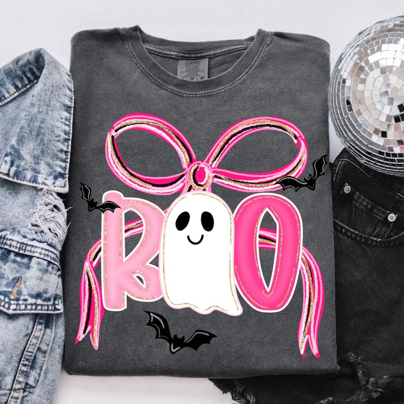 May include: Dark gray sweatshirt with a pink bow and the word "BOO" in pink letters. A white ghost with a smiling face is in the center. Black bats are scattered around the design. The sweatshirt is a comfortable, casual style.