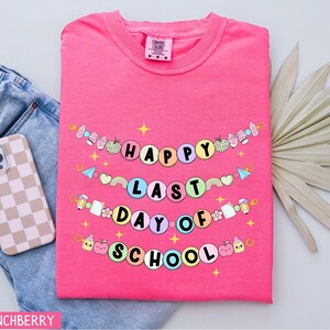 May include: Pink t-shirt with a colorful banner that reads "Happy Last Day of School".