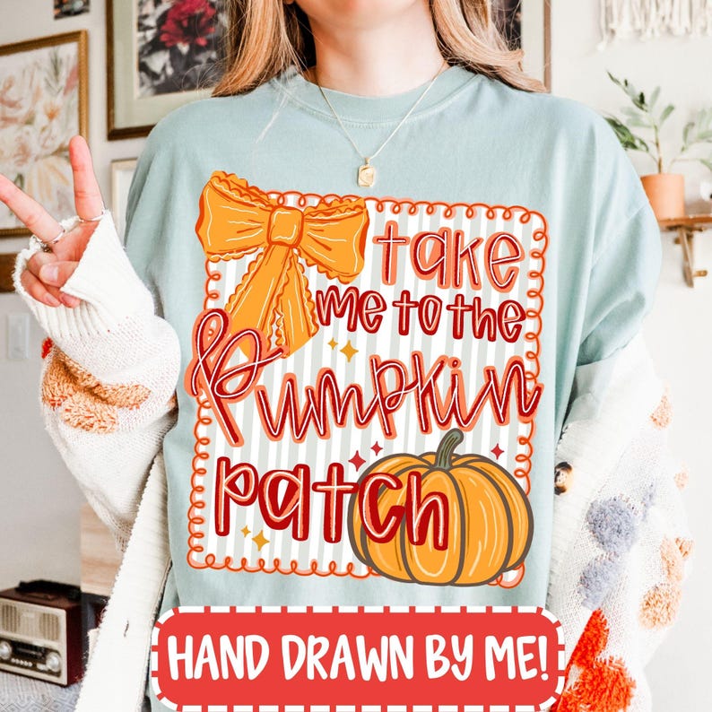 May include: A light blue t-shirt with the text "Take Me To The Pumpkin Patch" in orange and red script. The design includes an orange bow and a pumpkin illustration. The bottom of the shirt reads "Hand Drawn By Me!"