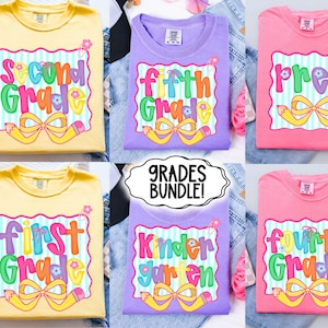 May include: A collection of colorful grade-themed t-shirts. Each shirt features a grade level, such as "Second Grade" or "Fifth Grade," in a playful font with a pencil and bow design. The shirts are in various colors, including yellow, purple, and pink.