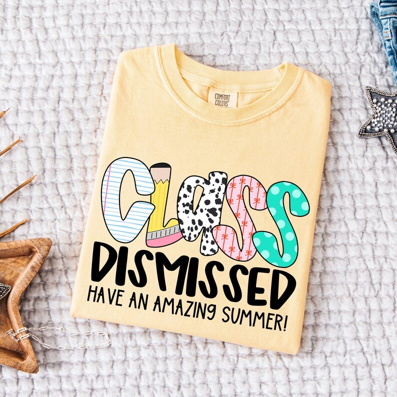 May include: A yellow t-shirt with the text "Class Dismissed Have an Amazing Summer!" in black lettering. The word "Class" is made up of colorful letters with different patterns.