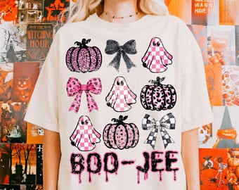 May include: Cream-colored t-shirt featuring Halloween-themed graphics. The design includes pink and black pumpkins, bows, and ghosts with checkered patterns. The text "BOO-JEE" is printed in a dripping font, perfect for the spooky season.