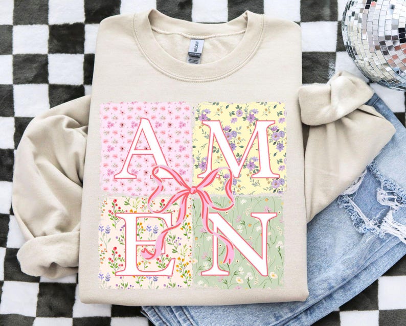 May include: A beige sweatshirt with a floral print design that spells out the word "AMEN".