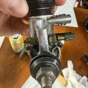 May include: A metal glow plug engine for remote control vehicles featuring a blue cooling head, a silver body with a prominent 29 marking, and a threaded drive shaft. The engine includes a carburetor assembly with brass adjustment needles.
