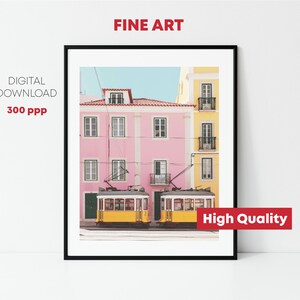 May include: A digital print of a photograph of two yellow trams parked in front of a pink and yellow building. The building has windows and balconies. The image is high quality and suitable for printing.