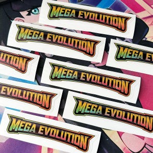 May include: Several rectangular stickers featuring the text "MEGA EVOLUTION" in a vibrant, multi-coloured font. The text is outlined in black, with a gradient from green to orange. The stickers are on a white background.
