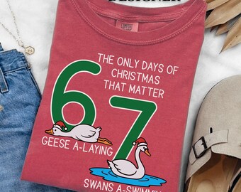 May include: Red t-shirt with the text "The Only Days of Christmas That Matter." The number 6 features a goose wearing a Santa hat, and the number 7 features a swan in a Santa hat. The text "Geese A-Laying" and "Swans A-Swimming" are also included.