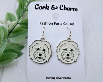 Puede incluir: Pendientes colgantes de cabeza de perro blanca con ganchos de plata de ley. Los pendientes están en una tarjeta blanca con el texto "Cork & Charm" y "Fashion For a Cause!" La tarjeta también dice "Sterling Silver Hooks".