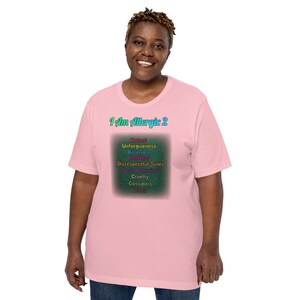 Puede incluir: Una camiseta rosa con el texto "I Am Allergic 2" en una fuente de colores. El texto está rodeado de un rectángulo verde con una lista de palabras en diferentes colores, incluyendo "Hatred", "Unforgiveness", "Bitterness", "Jealousy", "Disrespectful Tones", "Nasty Behaviors", "Cruelty", "Gossipers" y "Liars".