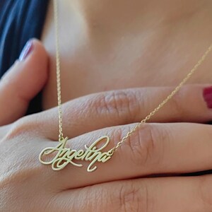 May include: A gold necklace with a cursive nameplate pendant that reads "Angelina".