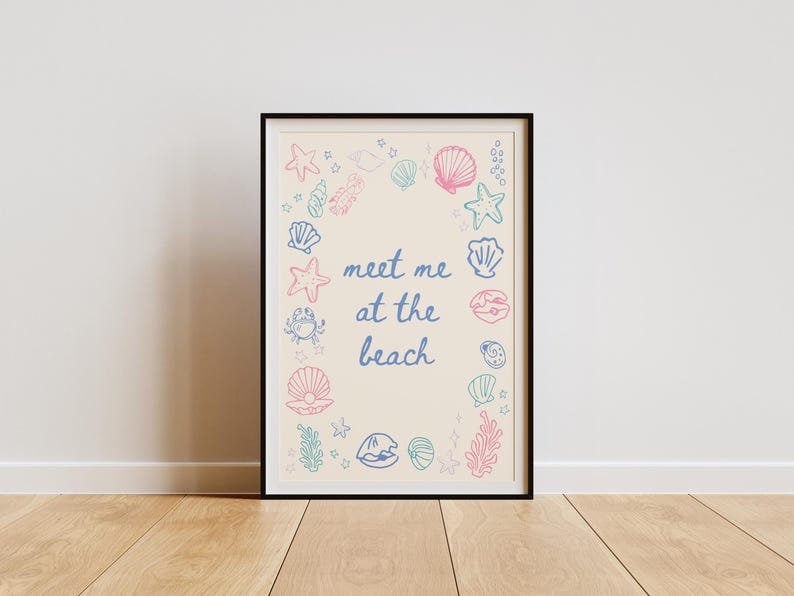 May include: A framed print with a cream background and a blue and pink illustration of seashells, starfish, and seaweed. The text "Meet me at the beach" is written in blue cursive.